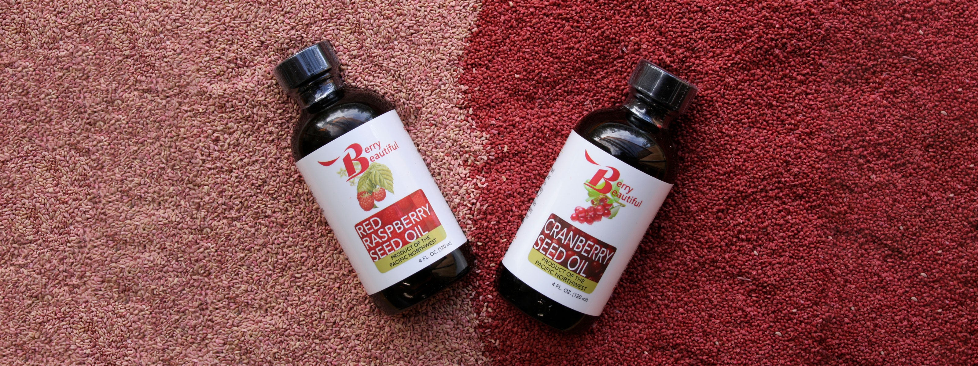 Berry Beautiful red raspberry seed oil and cranberry seed oil displayed on top of the seeds they were cold-pressed from.