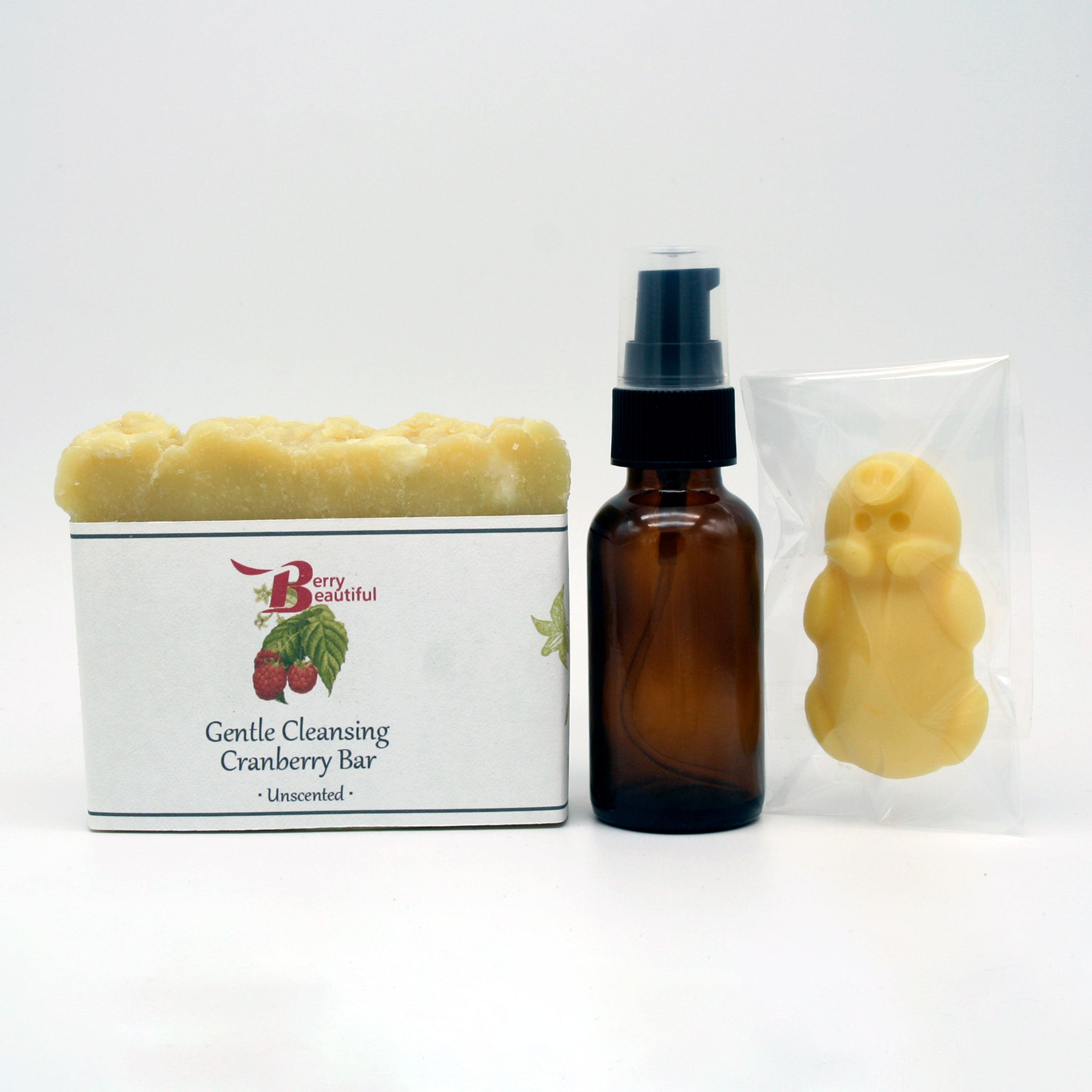 Berry Beautiful Gift Box featuring a brown pump bottle of infused oil, pig-shaped moisturizing body bar, and gentle cleansing cranberry soap bar.